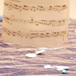 Notenblatt auf einem dekorierten Tisch, umgeben von musikalischen Accessoires und einer warmen Tischdekoration, ideal für Musikliebhaber und kreative Veranstaltungen.
